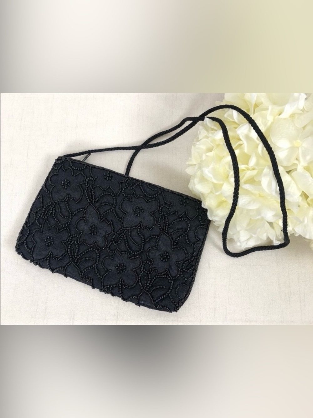 black beaded handbag with a floral motif and zipper closure.